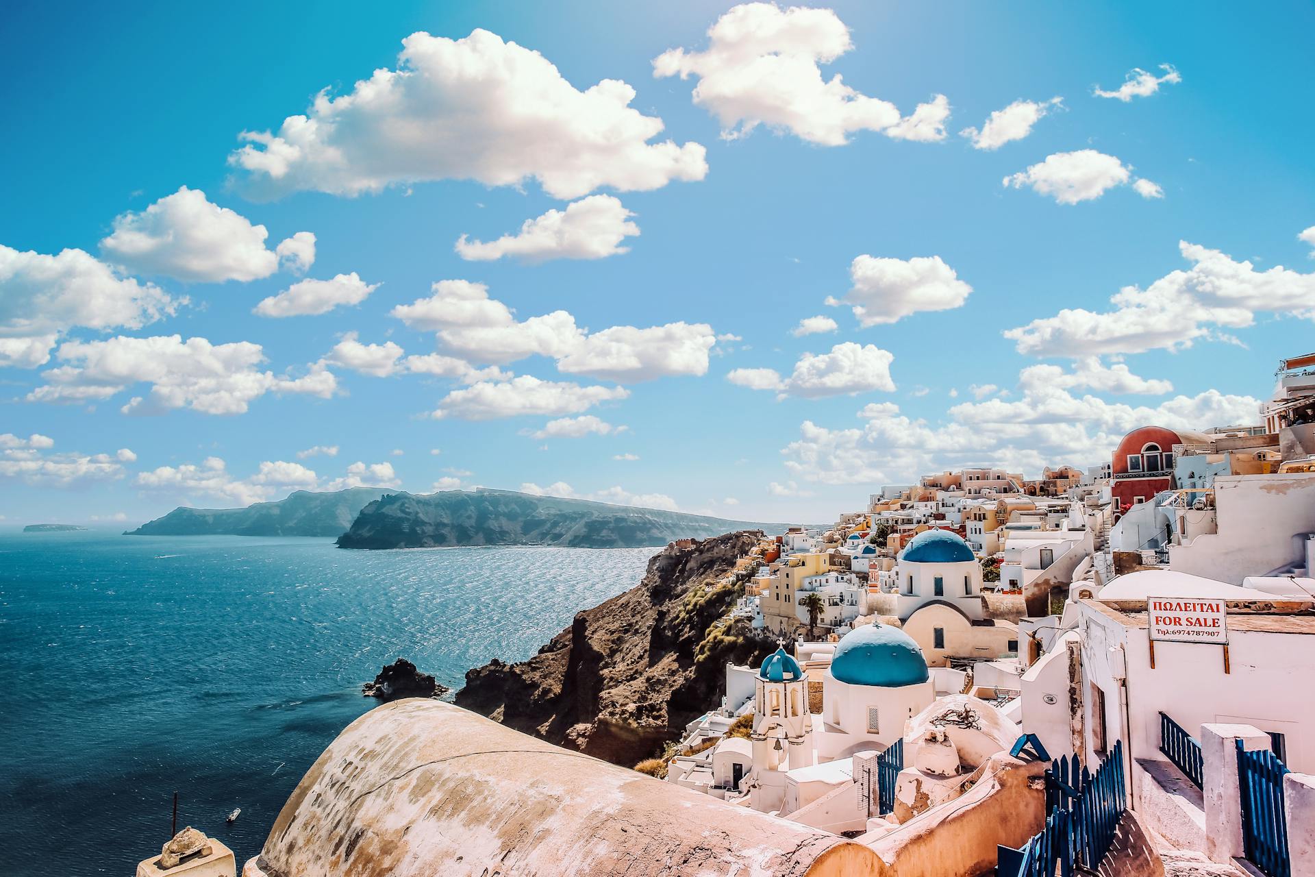 White Concrete House Near Body of Water Under White and Blue Cloudy Sky In Greece.
